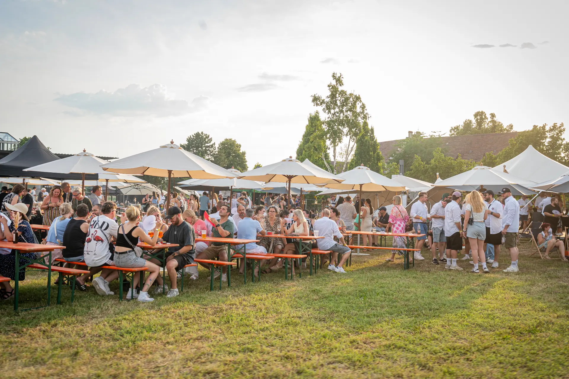 Gäste unter Sonnenschirmen auf dem Festivalgelände – Eventkonzepte der Flyingbar