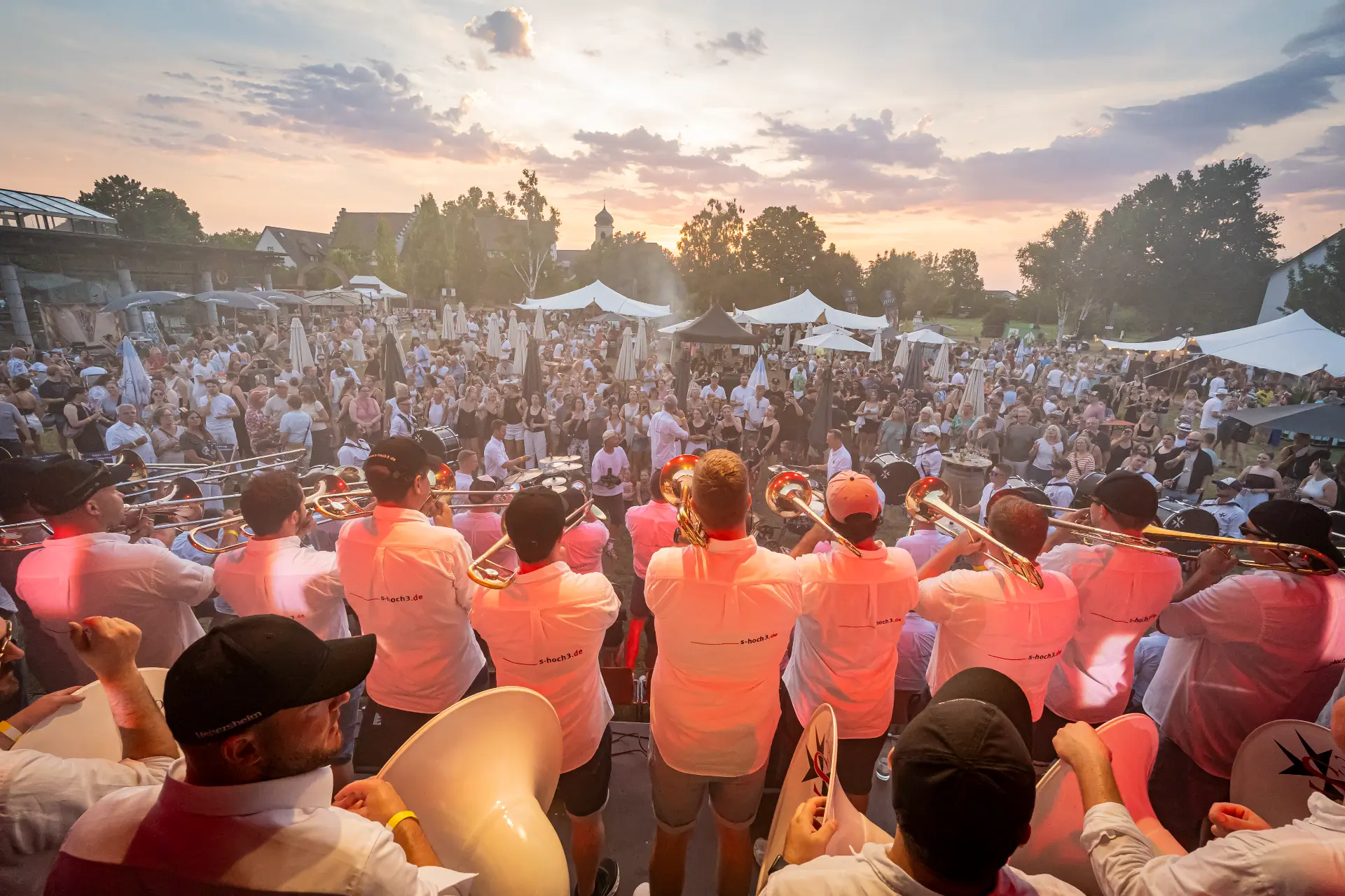 Brassband spielt bei Sonnenuntergang vor Festivalpublikum im Römerpark